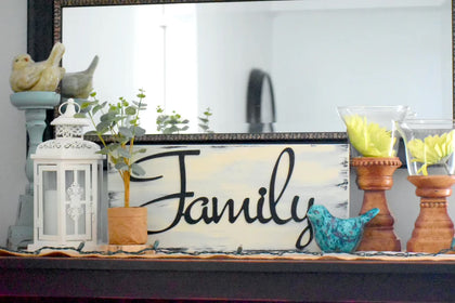 Wooden sign painted white with Family written across in a metal plaque.